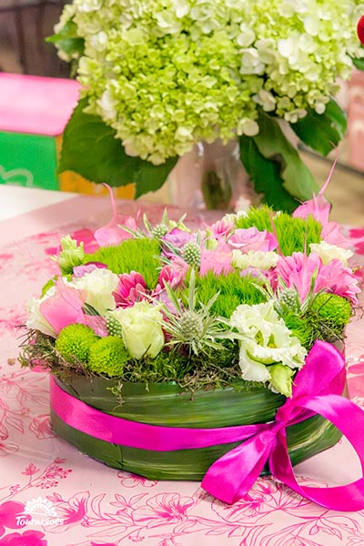 Composition de fleurs mixtes dans des tons roses, blancs et verts et un pot naturel fait d'une feuille enroulée